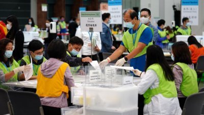 2021年香港特区选举委员会界别分组一般选举结果周一清晨揭晓，412名候选人竞逐的13个界别分组中364席选委全部顺利产生。图为中央点票站工作人员检视选票。（图取自中新社）