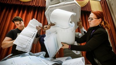 俄罗斯周日结束一连3天的国家杜马选举投票后，数名地方选举委员会的成员在投票站清空投票箱。（图取自法新社）