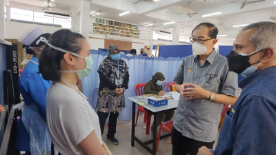 马汉顺（右2）在金宝中华华小疫苗接种中心，向医护人员了解接种计划进展，右为米奥。
