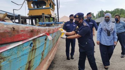 莫哈末苏菲安（前）为违例渔船喷漆后，再让当局人员展开销毁工作。