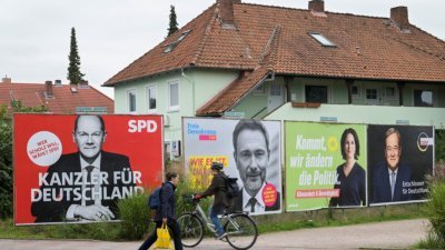 在德国汉堡，一民众走过有著本届大选各党总理候选人的巨型海报看板。左起为社民党的肖尔茨、自由民主党的林德纳、绿党的贝尔博克，以及基民盟的拉舍特。(图取自路透社)