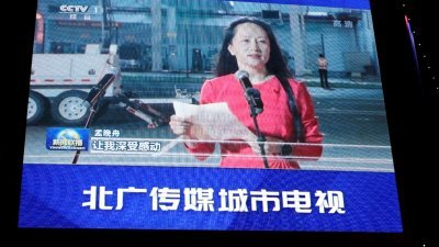 中国北京一家购物中心外，华为商店顶部的巨型屏幕上周六晚播放华为首席财务官孟晚舟返抵中国后讲话的新闻画面。（图取自路透社）