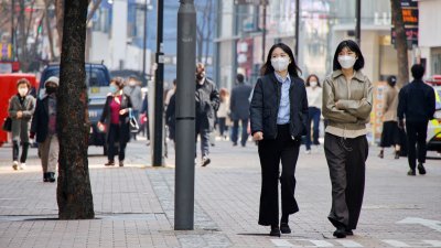 韩国民众戴著口罩，走在首尔的购物区。（图取自路透社）