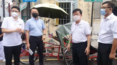 洪敏芝（左）陪同杨顺兴（左起）、曹观友及光大州议员郑来兴走访古迹区时，向媒体讲解有关三轮车提升维修工作进度。