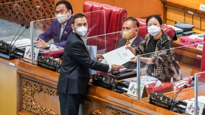 印尼国会通过性暴力犯罪法案后，议长马哈拉尼（右）接纳解决性暴力法案工作委员会主席威利的报告。（图取自安塔拉图片/路透社）