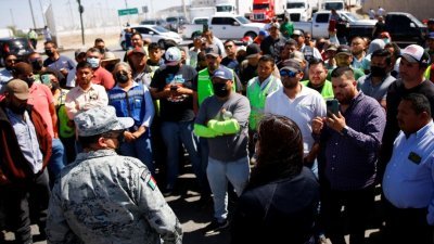 墨西哥的卡车司机周一封锁美墨交界处的萨拉戈萨-伊斯莱塔国际大桥，抗议得克萨斯州州长要求检查通行车辆命令，导致入境时间变长，墨西哥国民警卫成员到场与卡车司机交涉。（图取自路透社）