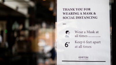 美国宾州费城一家酒店的用餐区，张贴著提醒客人戴口罩和保持安全社交距离的告示。（图取自路透社档案照）