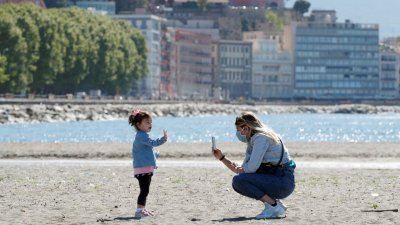 一名女子和小女孩在意大利那不勒斯的海滩上玩耍。（路透社档案照）