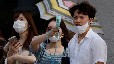热浪自6月底侵袭日本，为解暑民众只好随身携带小型电风扇及购买冰饮。（图取自路透社）