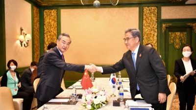 中国外长王毅（左）与韩国外长朴振出席在印尼巴厘岛举办的二十国集团（G20）外长会议，双方友好地握手并留下合影。（图取自韩国外交部）