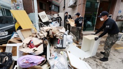 首尔暴雨过后，洪水从被淹没的房屋中排出，士兵们加紧善后工作。（图取自韩联社/路透社）