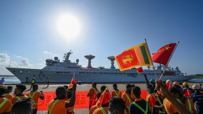 中国科考船“远望5号”周二抵达斯里兰卡南部的汉班托塔港，港口工人在码头上挥动两国国旗欢迎。（图取自法新社）