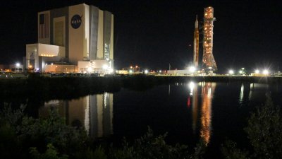 顶部为猎户座太空船的NASA下一代月球火箭，周二晚在佛罗里达州卡纳维尔角的肯尼迪航天中心，缓缓地离开飞行器装配大楼，开始慢动作前往发射台。（图取自路透社）