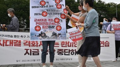 在首尔韩国战争纪念馆前举行反对韩美联合军事演习的集会上，抗议者举著标语牌，上面写著“停止联合军演！”（图取自法新社）