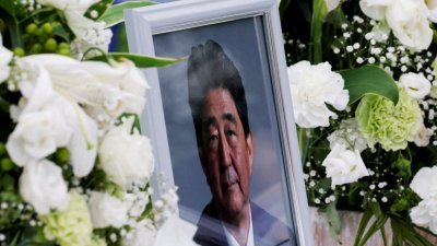 日本前首相安倍晋三7月8日遇刺身亡，自民党在东京的总部外摆放著安倍的遗照，让民众鲜花悼念。（路透社档案照）