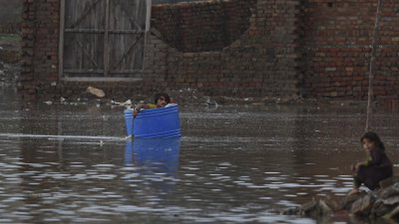周四暴雨过后，巴基斯坦信德省雅各布阿巴德的一名男子，坐在塑料桶内用树枝划水，穿过洪水泛滥的地区。（图取自法新社）