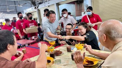 倪可敏（站者左）周日在后廊巴刹分派月饼予选民，与选民分享即将来临中秋节的喜悦。