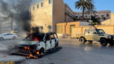 利比亚首都的黎波里的大街上，在上周六（27日）可见到因冲突起火燃烧的汽车。（图取自法新社）