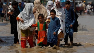 巴基斯坦洪水影响境内约3300万人，联合国今吁各界募集7亿款项协助救灾。图为一个巴基斯坦家族走在积水中。（图取自路透社）