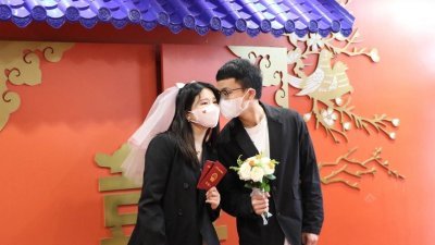 中国初婚人数大降，图为今年5月20日杭州一对新人在婚姻登记处拍照留念。（图取自中新社）