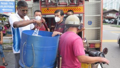 日落洞候任国会议员雷尔（左）协助义务消防队将水源装入民众的水桶。