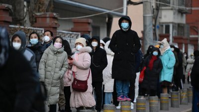 中国北京市内陆续撤除检测站，导致市民身穿厚重的羽绒服，带著围巾和帽子，在严寒天气中大排长龙做核检。（图取自法新社）