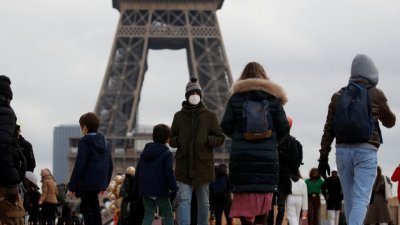 戴著口罩的民众，在巴黎地标埃菲尔铁塔附近的特罗卡德罗广场行走。（图取自路透社）