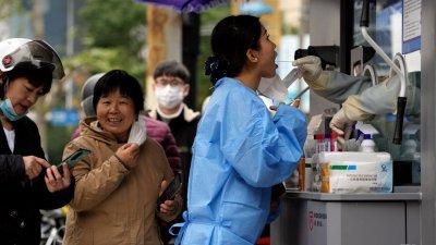 在中国上海的一核酸检测点，一名妇女周三在进行新冠肺炎病毒检测。（图取自路透社）