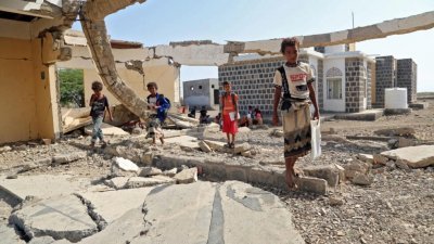 在饱受战争蹂躏的也门西部省份荷台达，学童在今年新学年首日，站在一所严重受损的学校前。（法新社）
