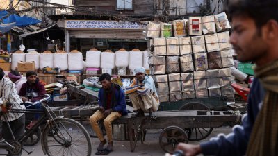 印度民众的生活已恢复正常，几名工人在印度德里老城区的批发市场，坐在手推车上，脸上不再戴有口罩。（图取自路透社）