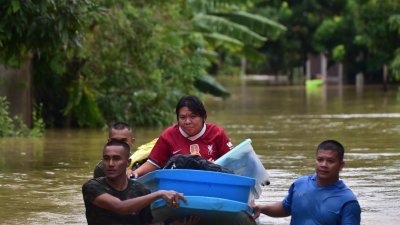 在泰国南部陶公府的Lampu村，军方人员用小船穿越洪水运送受灾灾民。（图取自法新社）