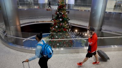在美国佛罗里达州的迈阿密国际机场，旅客经过一颗圣诞树。迈阿密国际机场预计今年将是一个繁忙的冬季假期旅游季，从12月21日到1月6日，预计客运量将达到250万人次，比2021年创纪录的时期增长1.5%。（图取自法新社）