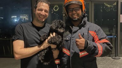 狗主抱著爱犬与其中一名消防员合影。 （取自《慈母舰》）