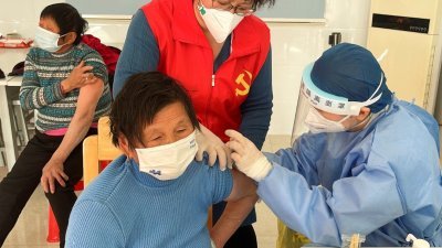 日前在中国上海市郊村庄的疫苗接种中心，医务人员为老年居民们接种新冠疫苗。（图取自路透社）