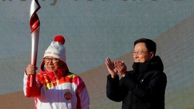 北京冬奥会火炬接力启动仪式周三在北京奥林匹克森林公园举行，中国副总理、冬奥会工作领导小组组长韩正（右）将火炬递给第一棒火炬手罗致焕。（图取自路透社）