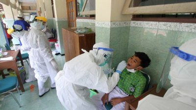爪哇省梭罗市一所高中在发现一宗冠病确诊病例后，医护人员为全体师生进行聚合酶连锁反应（PCR）检测。（图取自法新社）
