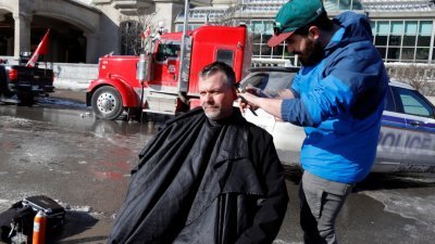 在渥太华货车司机聚集的抗议现场，有理发师为司机和支持者们理发。（图取自路透社）