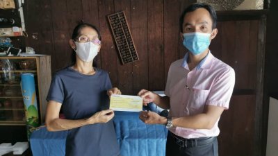 梁丽珍（左）从记者李文艺手中接领支票时，感谢《东方日报》热心读者的捐款。