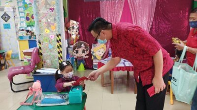 2.萧康骏（右）派发祝福红包及年柑给团结局幼儿园的小朋友，让他们度过一个温馨的新年。