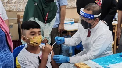 诺阿兹米（右）巡访设于峇眼色海斯里士林星礼堂的儿童疫苗接种中心，并现场为数名儿童接种疫苗。