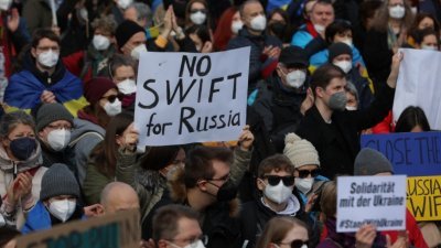 在德国法兰克福当地时间周六举行的反俄罗斯入侵乌克兰的集会上，一名抗议者举著标语牌，上面写著“俄罗斯没有SWIFT”。（图取自法新社）