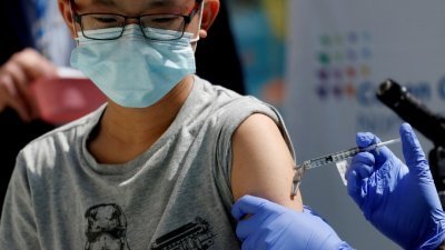 图为一名13岁华裔少年去年5月，在纽约一家儿童医疗中心接种辉瑞疫苗的档案照。（图取自路透社）