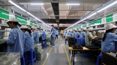 员工在东莞一家生产游戏控制器的工厂工作。（图取自路透社）