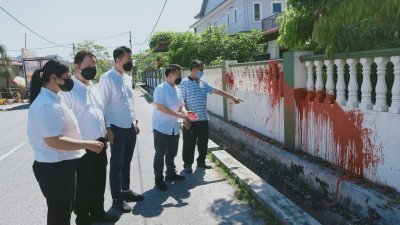 刘荣福（左5）向刘国南（左4）等人，讲述住家遭人泼红漆后，一大片围墙遭红漆染污。
