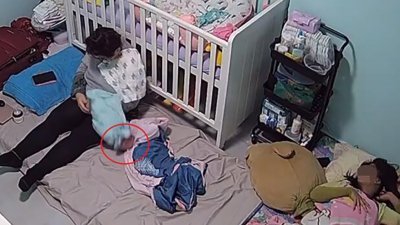 陪月嫂被指抱著女婴哄入睡，自己也睡著了，导致女婴（红圈）从陪月嫂怀里跌在床褥上。