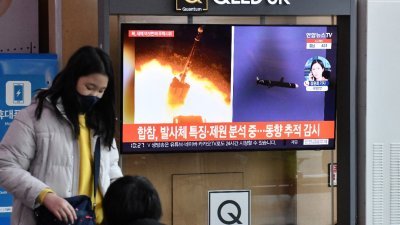 周四上午，韩国军方表示，侦测到朝鲜向东部海域发射两枚疑似弹道导弹。图为在首尔火车站，一名女子在等待登上列车，电视荧幕上出现朝鲜发射飞行物的新闻。（图取自法新社）