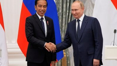 印尼总统佐科（左）于周四会见俄罗斯总统普京，两人面带笑容握手示好。（图取自路透社）