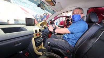 阿汉峇峇试乘一辆由传统轿车改装的电动车。