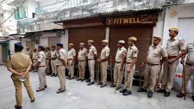 在拉贾斯坦邦乌代浦尔的一名印度教裁缝被杀后，当地警方不松懈，时刻派驻警员在社区巡逻。图为一队警员站在遇害裁缝的门店前。（图取自路透社）
