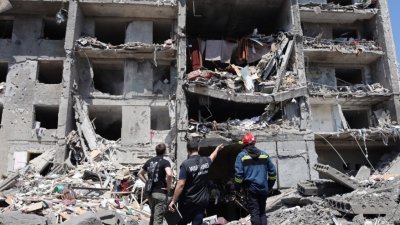 乌克兰指摘俄罗斯军队发射的导弹，周六清晨击敖德萨一座公寓，房屋被摧毁，酿成至少21人死亡。图为一名战争罪检察官（中）、一名救援人员（右）和一名平民站在被摧毁得面目全非的公寓前。（图取自法新社）